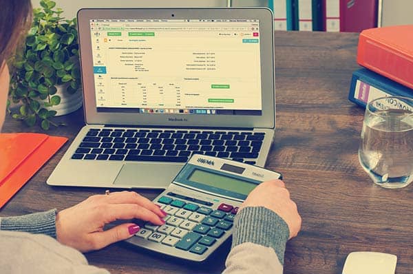 woman at laptop computer with handheld calculator