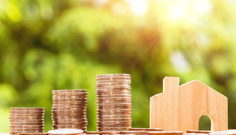 a wooden block shaped like a house next to three stacks of quarters