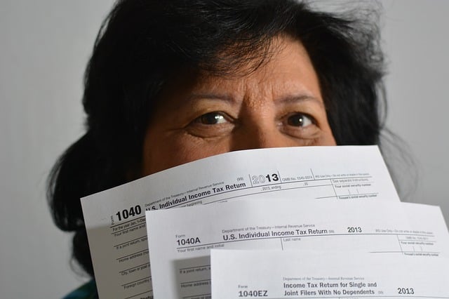 a woman holds 1040 tax return papers in front of her face