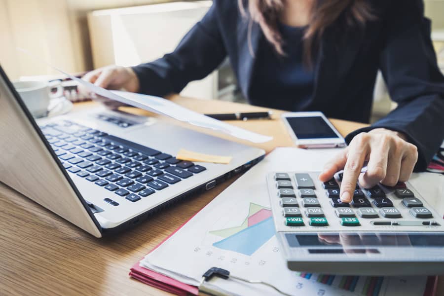 A woman uses a calculator while looking at papers at her desk