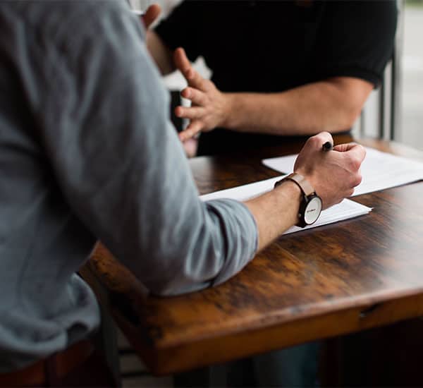 two people at a wooden table converse