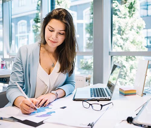 A woman in a light blue cardigan works at her desk