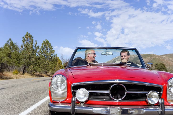 Men driving red convertible